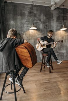 Man teaching a boy to play guitar in a contemporary music studio.