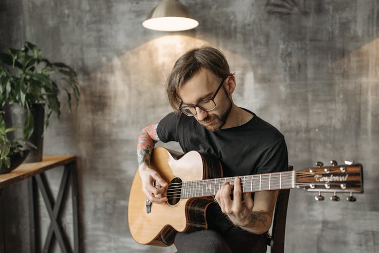 A Man In Black Shirt Playing Guitar