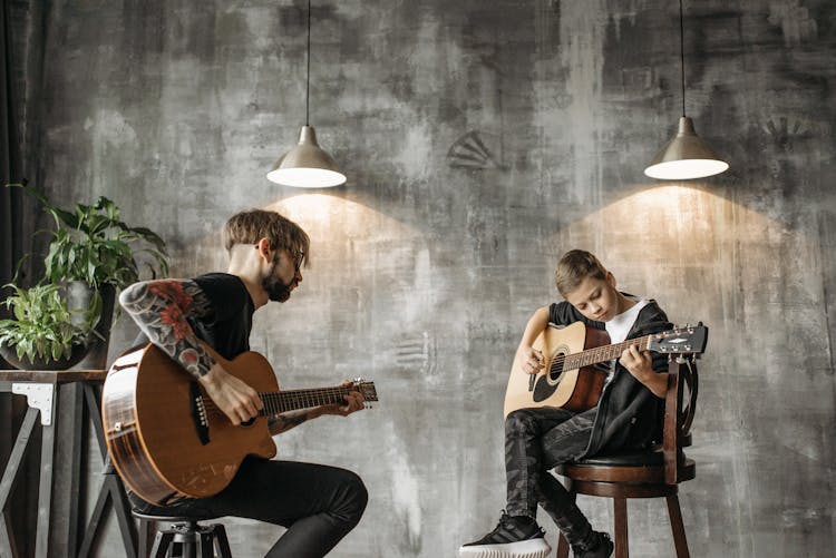 Man Teaching A Boy How To Play Guitar