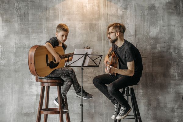 Lektor učí žiaka hrať na gitare
