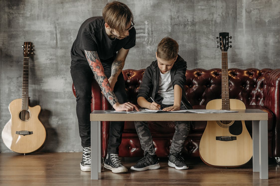 Free Man Giving a Guitar Lesson to a Boy Stock Photo