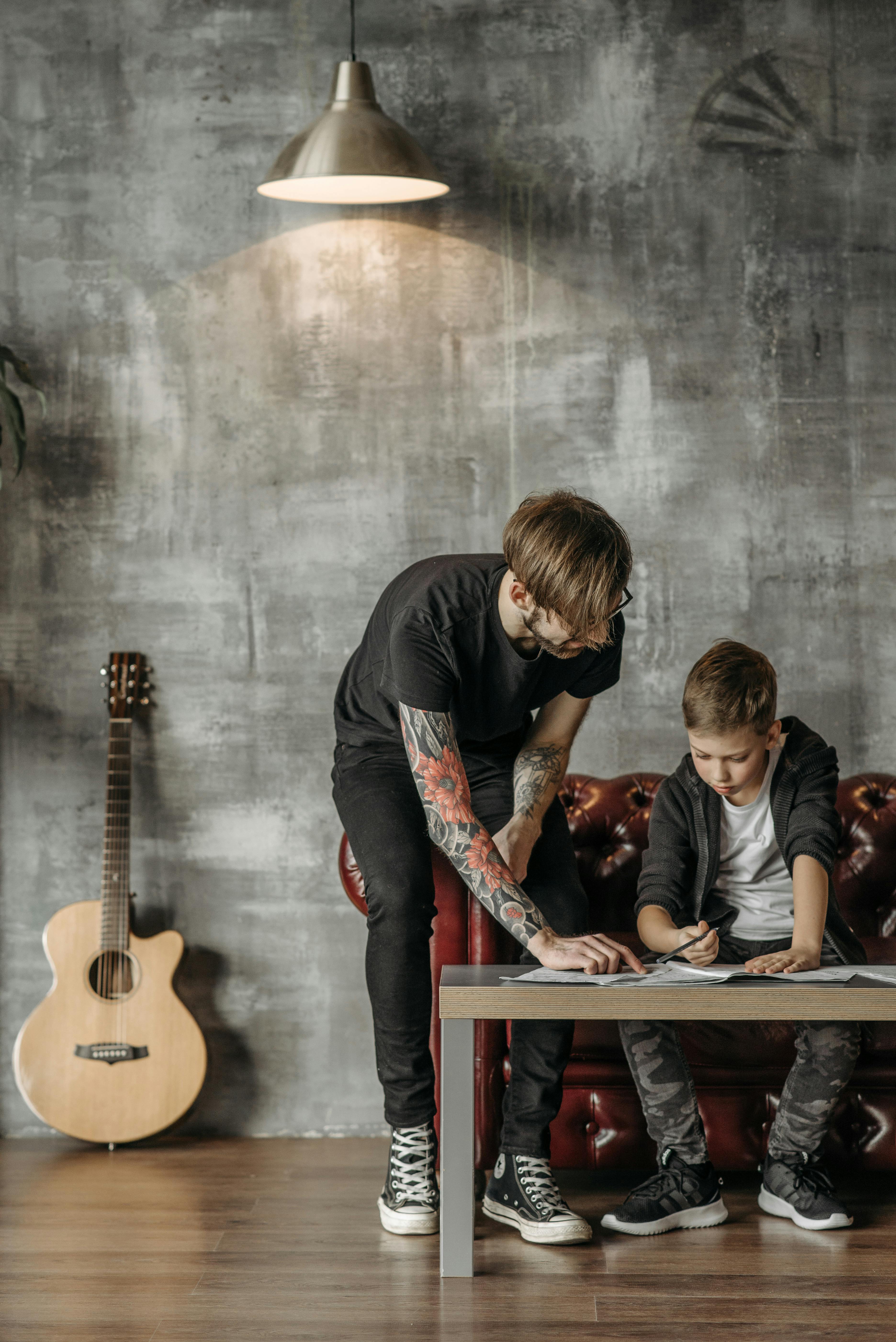 a man helping a boy study guitar lesson