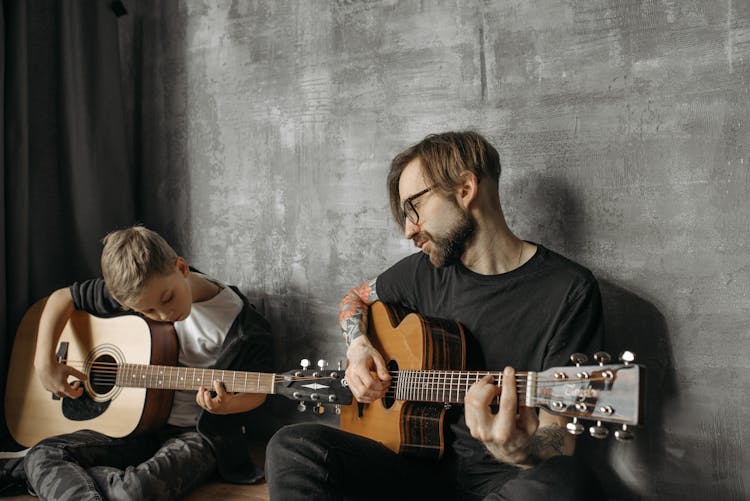 Man Teaching A Child To Play A Guitar