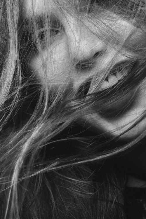 Free Grayscale close-up of a woman smiling with hair blowing across her face. Stock Photo