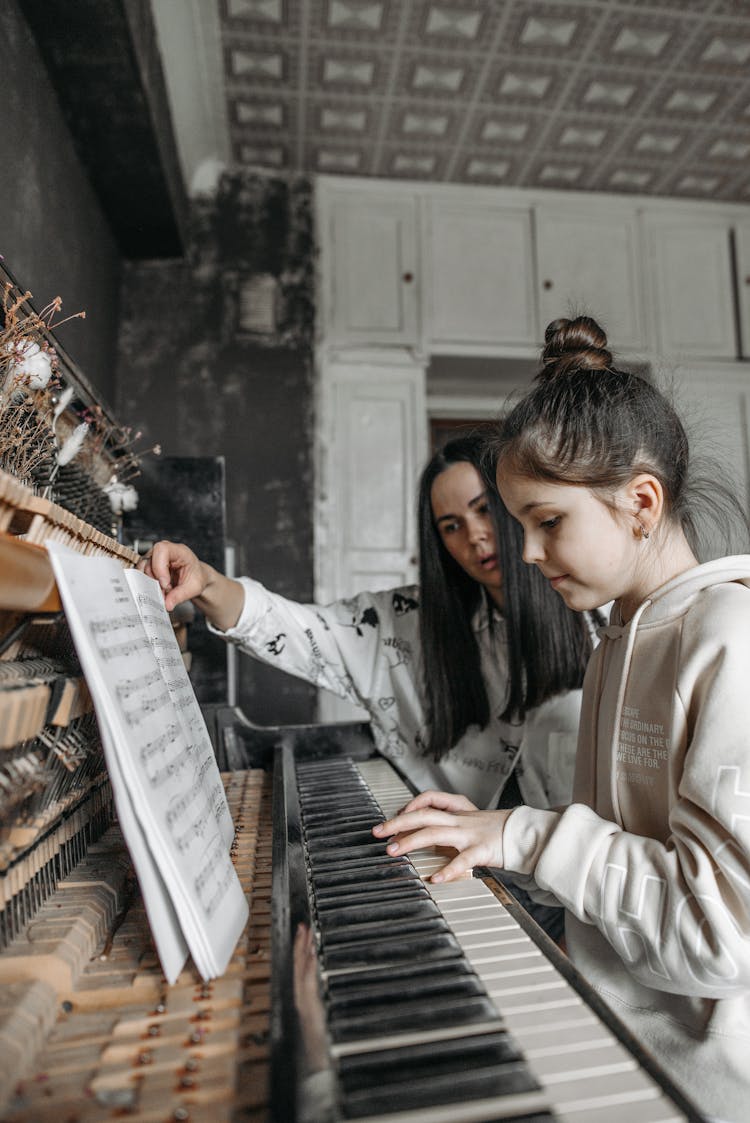 Woman Teaching The Girl How To Play A Piano 