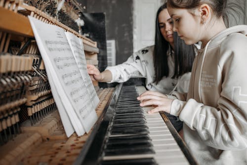 Free Girl in Beige Hoodie Playing Piano Stock Photo
