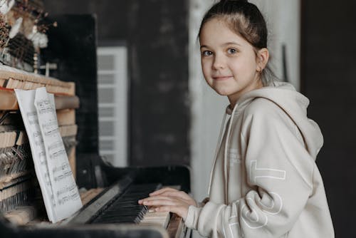 Close-Up Shot of a Girl in Beige Hoodie Jacket Playing a Grand Piano