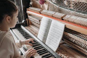 Woman in White Long Sleeve Shirt Playing Piano