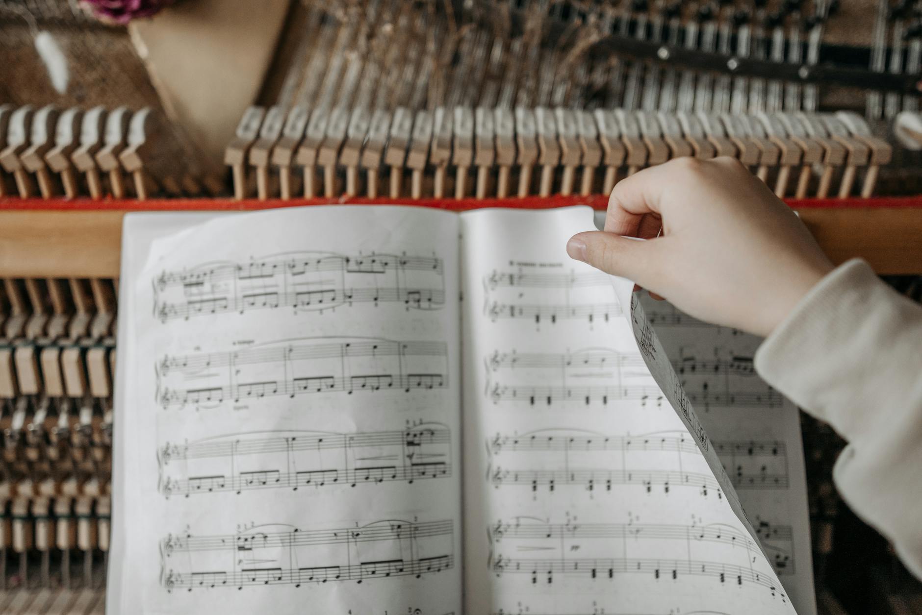 A hand turning a page of sheet music on a piano in an intimate setting.
