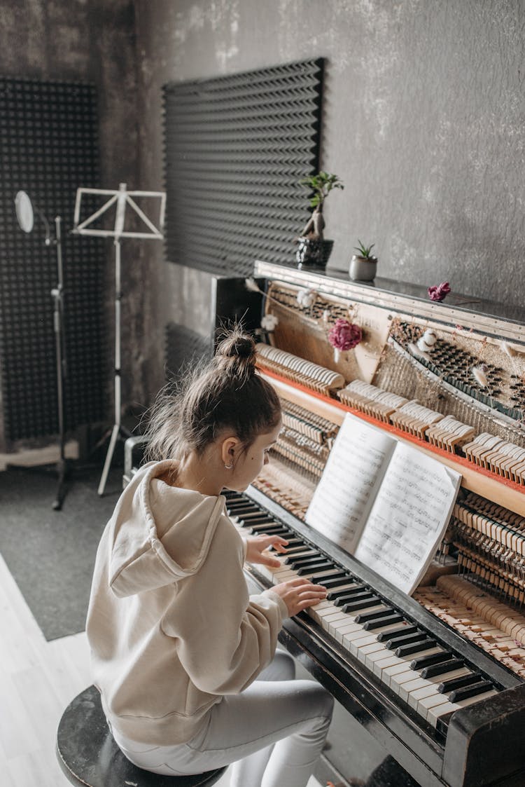 Girl In Beige Hoodie Jacket Playing A Piano