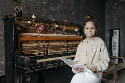 Young girl in a music studio sitting with music sheets near a vintage piano.