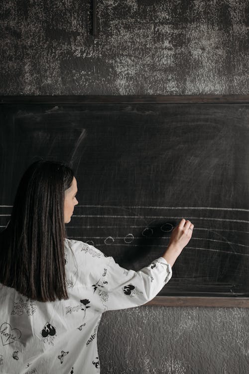 Free Woman wearing Sweater Writing on a Blackboard Stock Photo