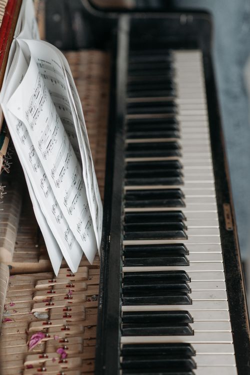 Free A detailed view of piano keys accompanied by an open music book, showcasing musical elegance. Stock Photo