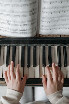 Child playing piano with sheet music above, focusing on hand placement and notes.