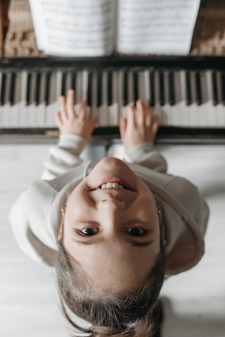 Top View Of A Girl Looking Up While Playing Piano 