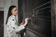 Woman in White and Black Floral Robe Standing Beside Black Wall