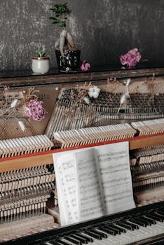 Elegant photo of piano interior with music sheets and decorative plants, offering a vintage aesthetic.