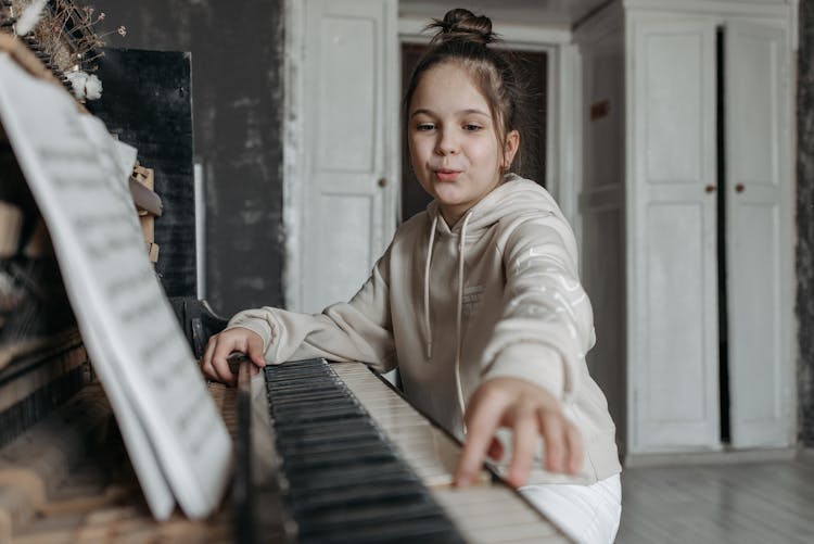 A Girl In Beige Hoodie Playing Piano