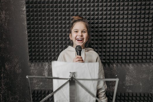Young girl singing into a microphone during a music lesson in a studio.
