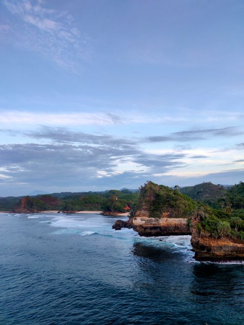 Free A breathtaking aerial view of Batu Bengkung Beach's cliffs and seashore in Malang, Indonesia, at daytime. Stock Photo