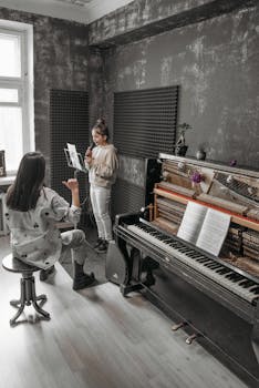 A music teacher guides a girl in an indoor piano lesson.