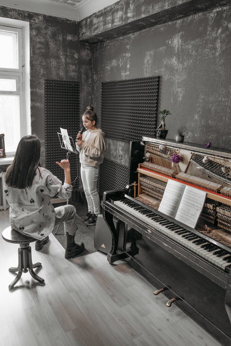 A Teacher Teaching A Girl How To Sing