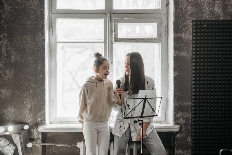 A Woman Teaching A Girl How To Sing