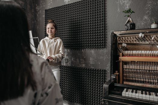 A young girl smiling during a music lesson in a studio with an open piano.