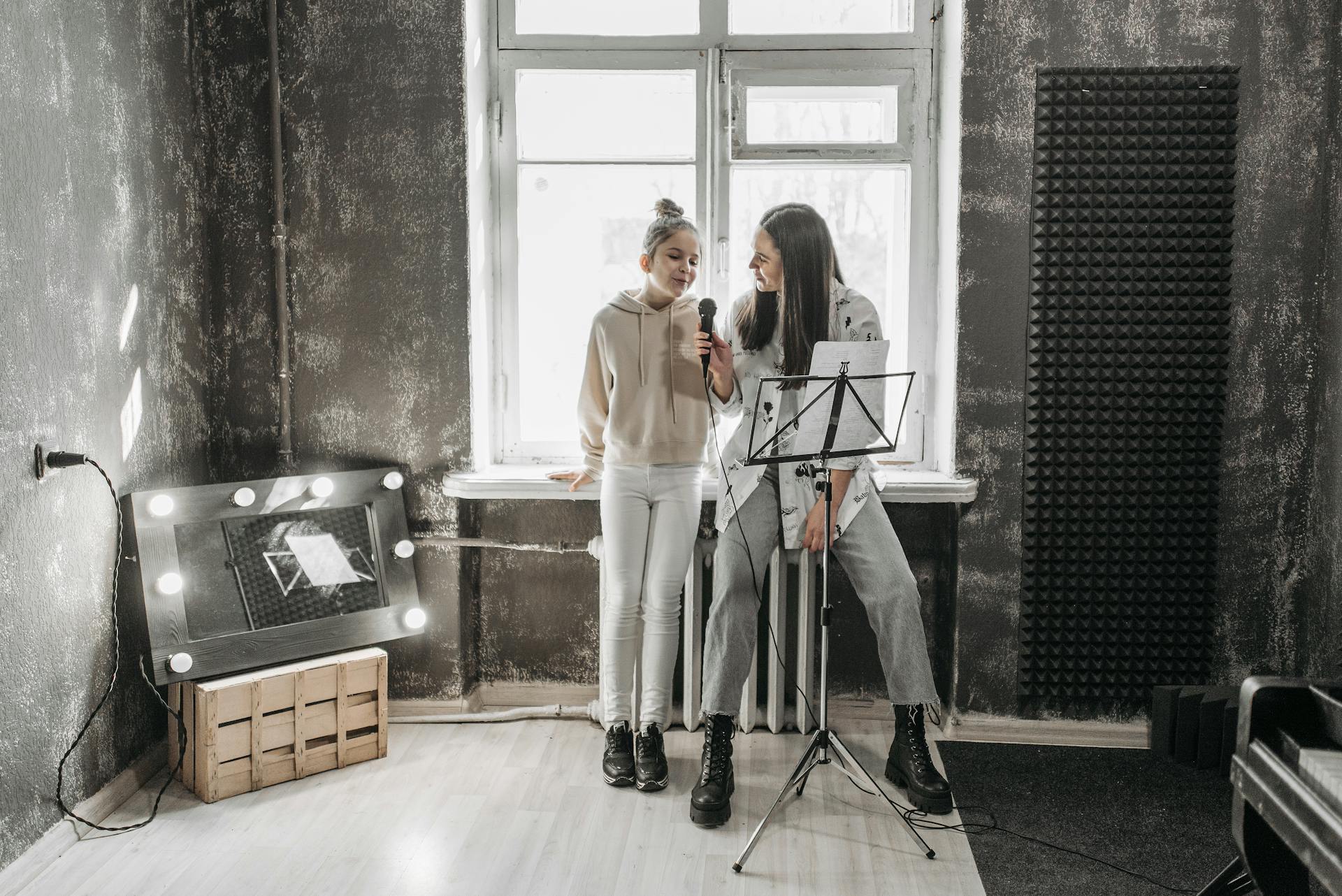 A teenager and teacher singing in a modern studio, enhancing vocal skills.