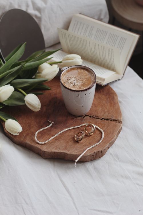 Free From above of gentle white tulips with green stems and leaves on blossom near bijouterie on wooden board Stock Photo