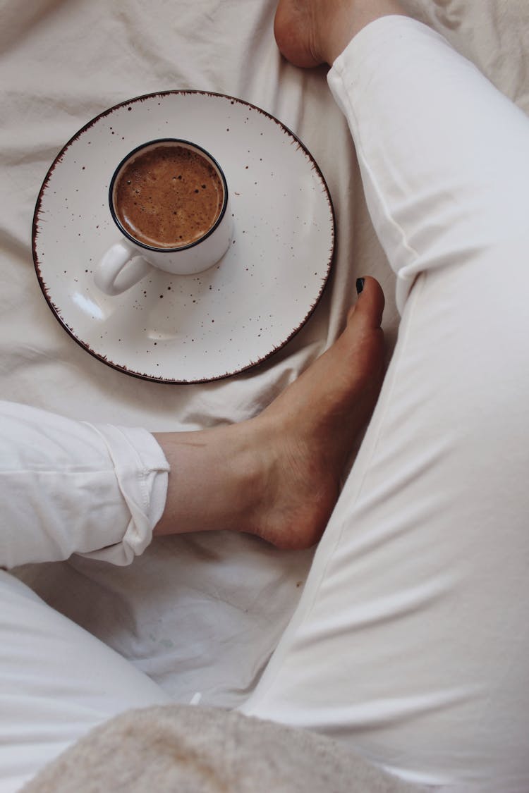 Unrecognizable Woman Drinking Hot Beverage On Bed In Morning