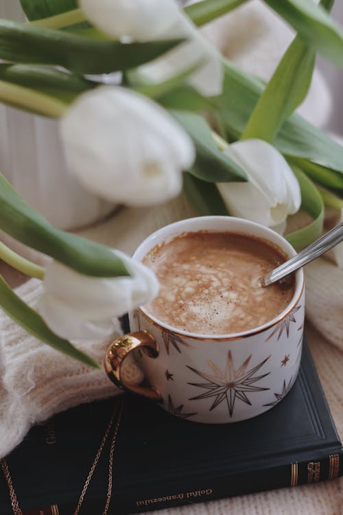 Free Cup of cacao placed on book near tulips bouquet Stock Photo