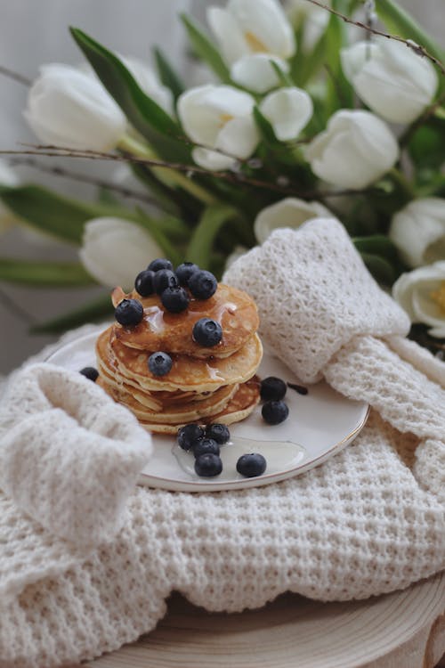 Free Yummy pancakes with berries in plate placed on knitted cardigan Stock Photo