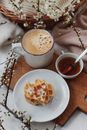 Cup of cacao with waffles and honey served on bed near gentle flowers