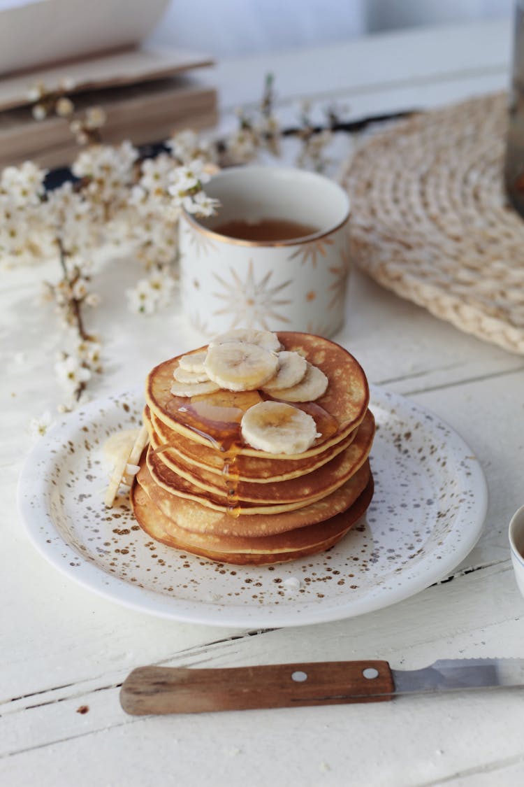 Homemade Pancakes With Syrup And Bananas Served On Table With Teacup