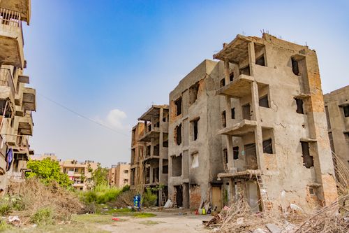 Free Abandoned concrete apartment buildings against a blue sky in Delhi, showcasing urban decay. Stock Photo