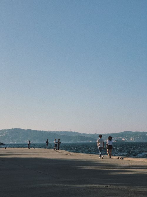 Free A serene view of people walking along the Sarıyer seaside with a clear blue sky. Stock Photo
