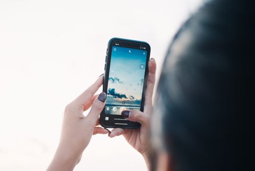 Free Close-up of hands photographing a scenic sky using a smartphone outdoors. Stock Photo
