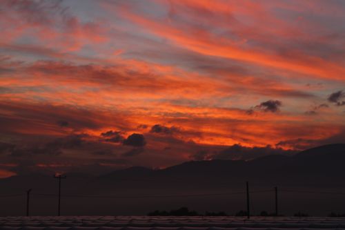 Free Empty road with electricity transmission going along silhouettes of mountains and cloudy sky in evening at sunset Stock Photo