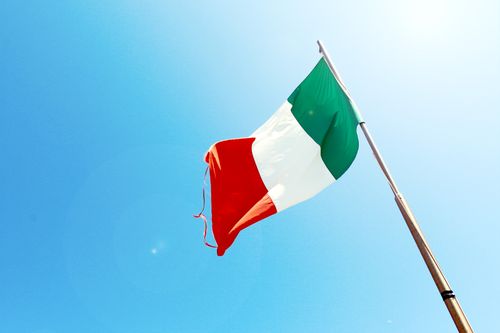 Free Vivid image of the Italian flag waving on a flagpole against a bright blue sky. Stock Photo