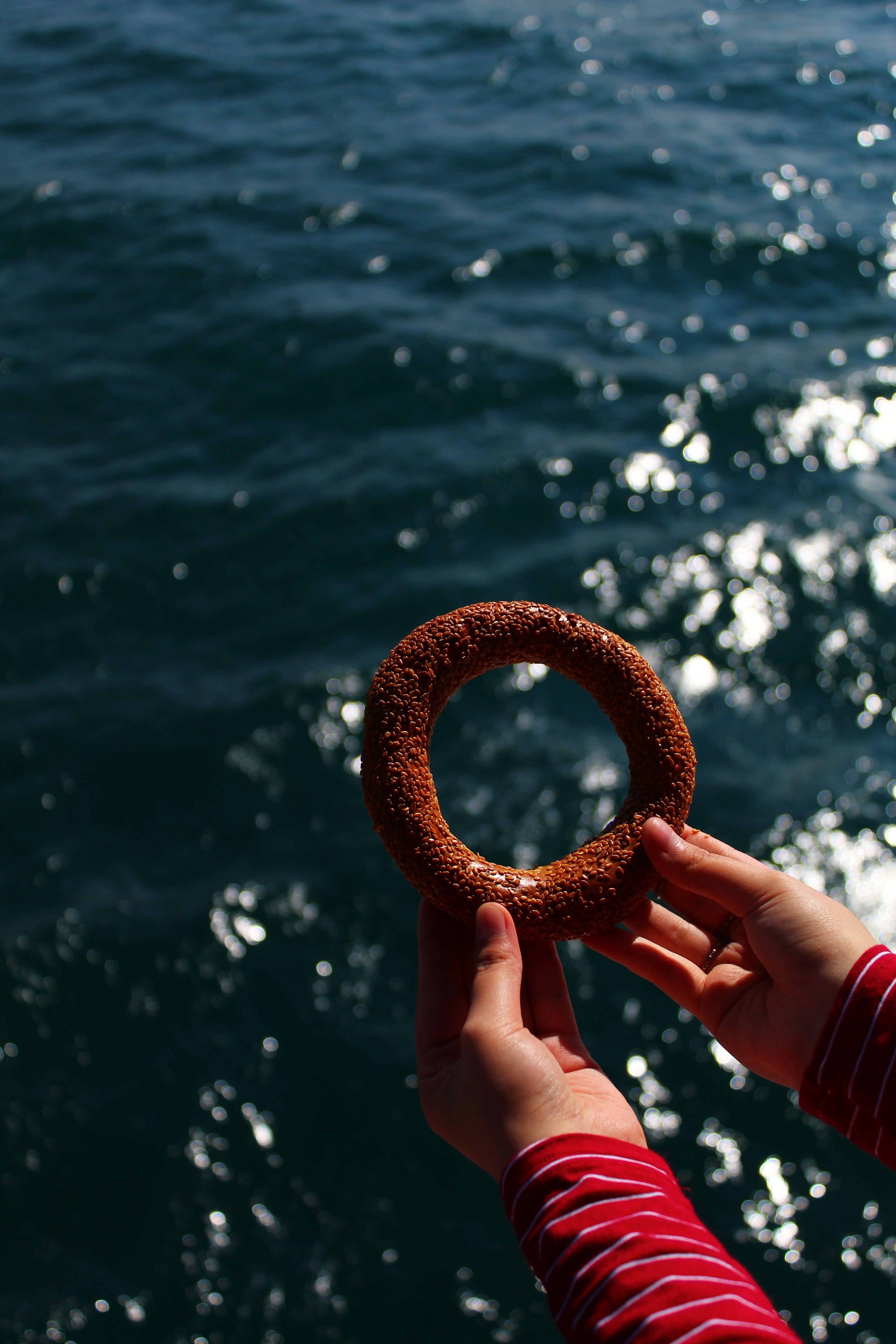 crop person with bagel on background of seawater