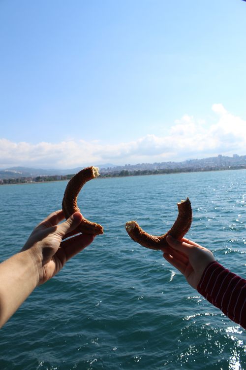 Free Anonymous person holding halves of bagel in hands against seascape with cloudy blue sky Stock Photo