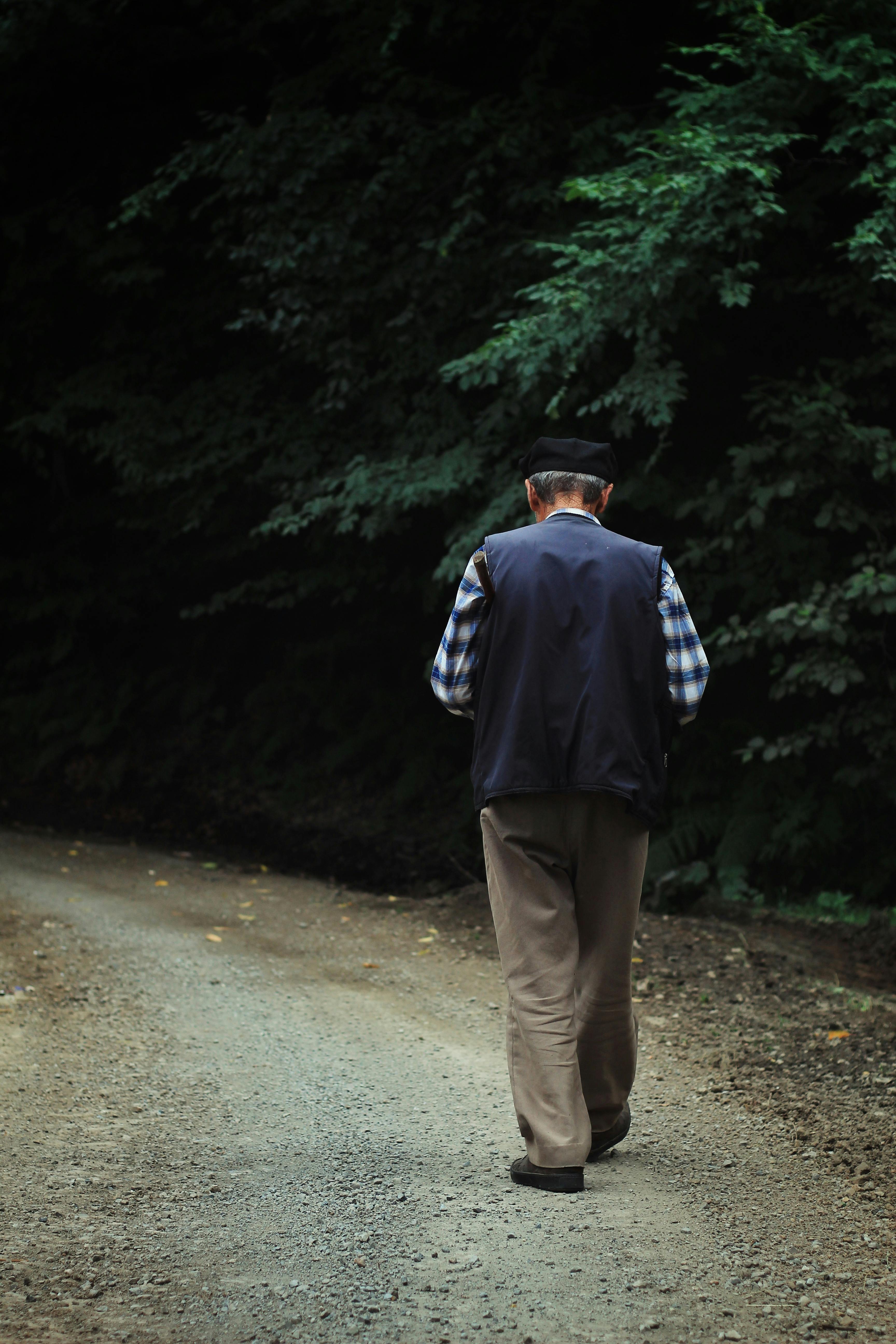 Elderly man walking along a forest road