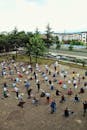 Crowded square with Muslim males gathering on paved ground on small rugs while praying on summer day