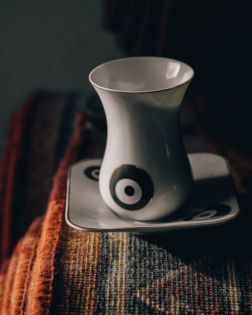 Free Porcelain cup of hot aromatic coffee on white saucer placed on colorful vintage carpet on daylight Stock Photo