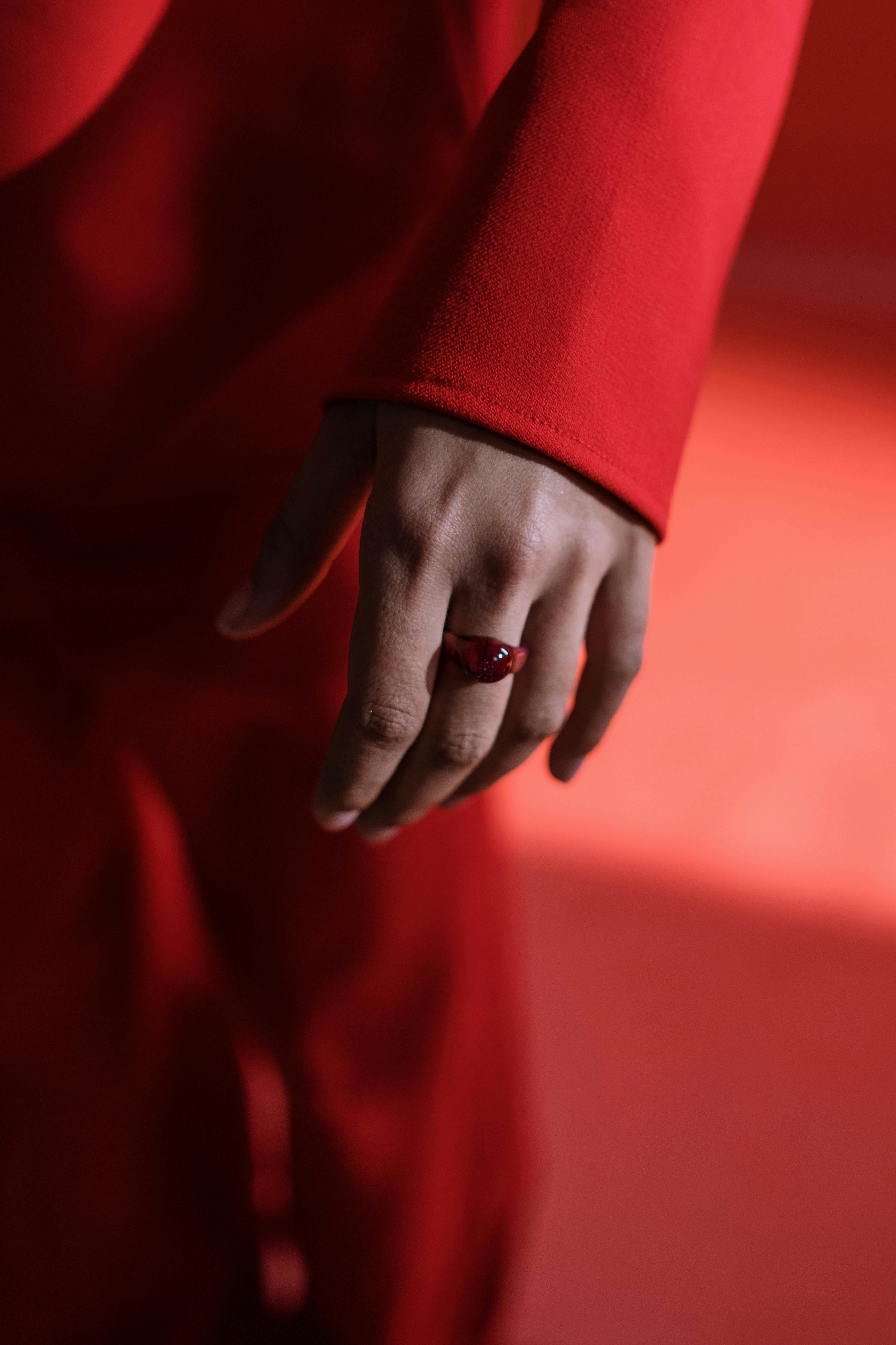 Artistic shot of a hand wearing a red ring and sleeve, emphasizing color and mood.