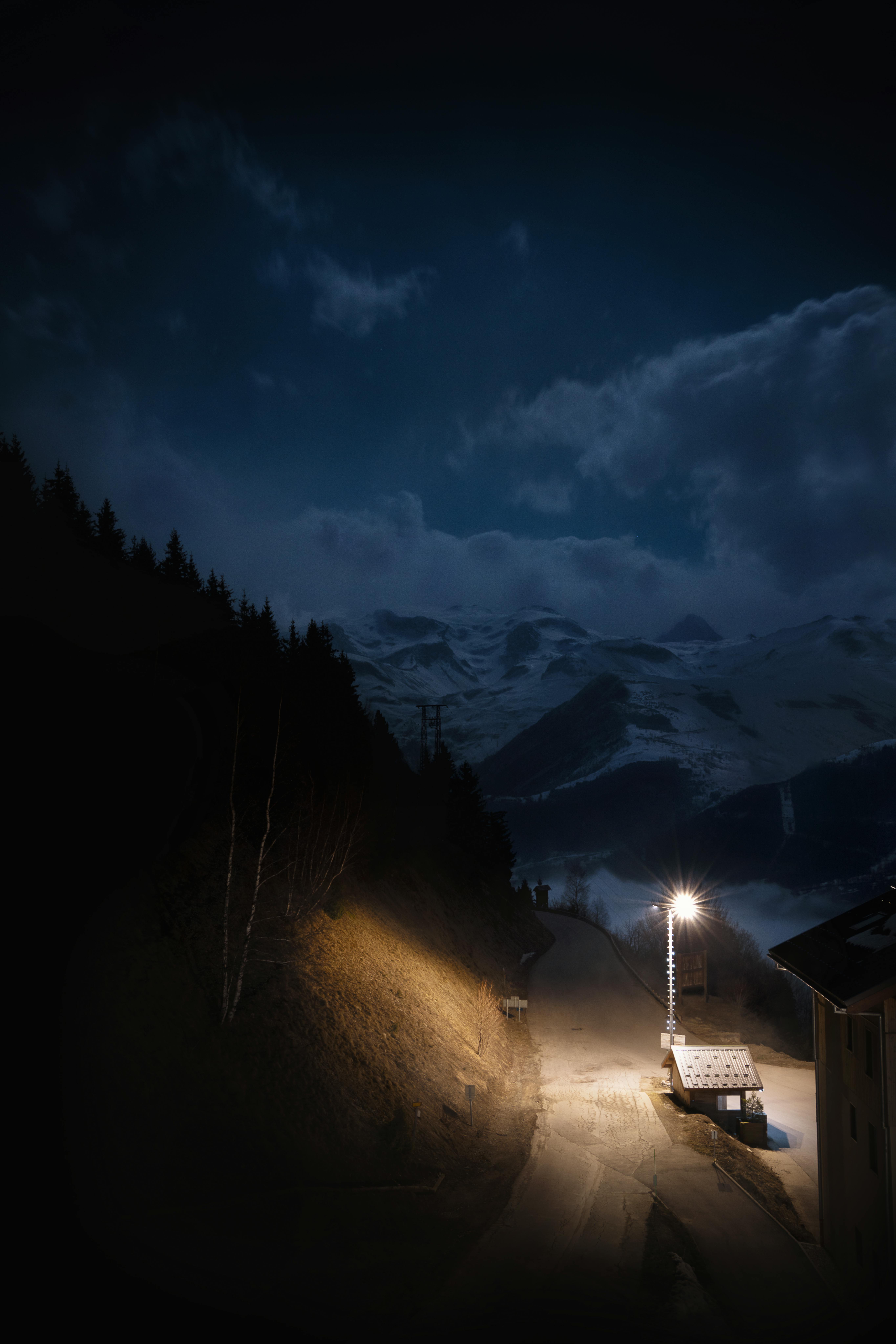 A peaceful night view of a snowy road and mountains in Auris, France.