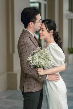 A loving couple shares a tender moment holding a bouquet of flowers.