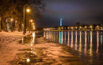 闪闪发光的灯照亮了白雪皑皑的城市河岸，倒映在水面上