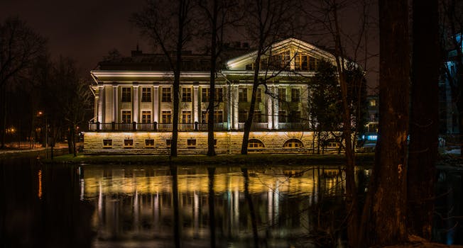 夜晚，一座灯火辉煌的豪宅倒映在宁静的湖泊和周围的树木中